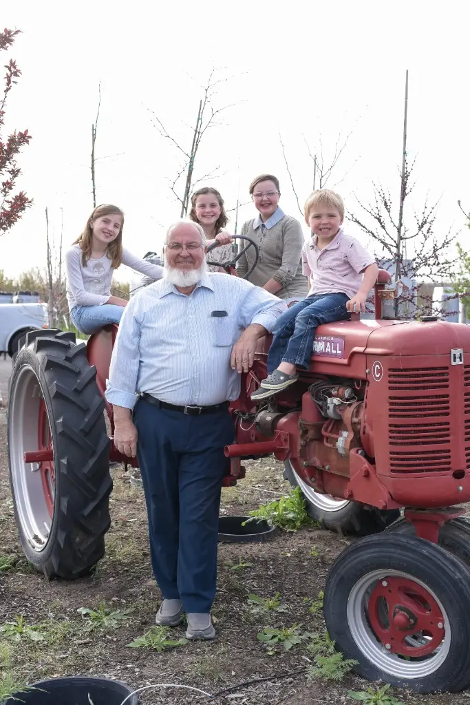 Everett with children posing on a red Farmall tractor